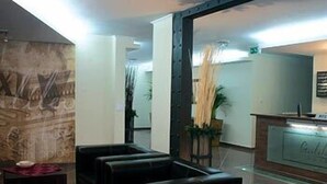 Zona de recepción con mostrador, sillas y una pared con un mural.