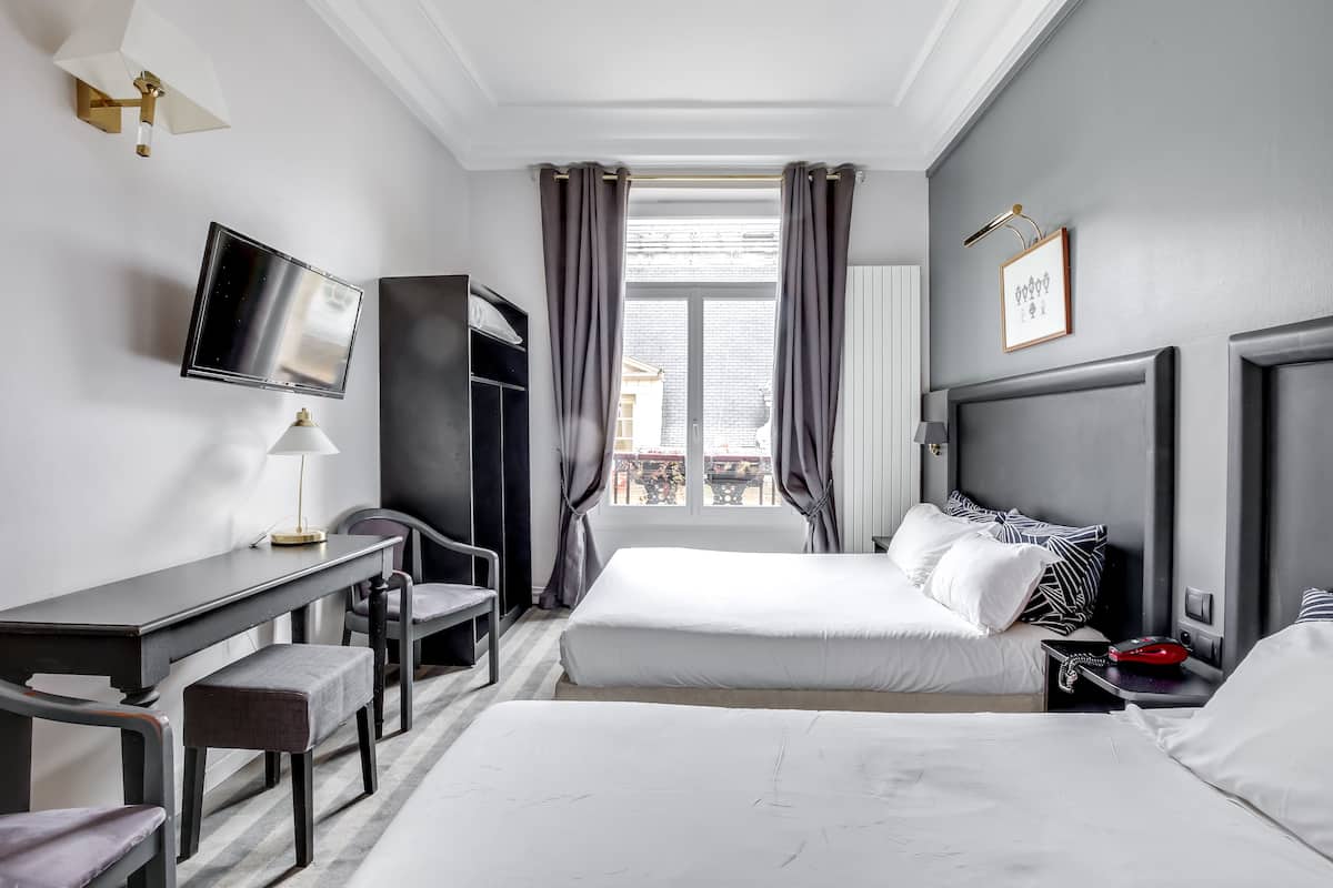 Una habitación de hotel moderna con una cama, escritorio, silla y televisor.