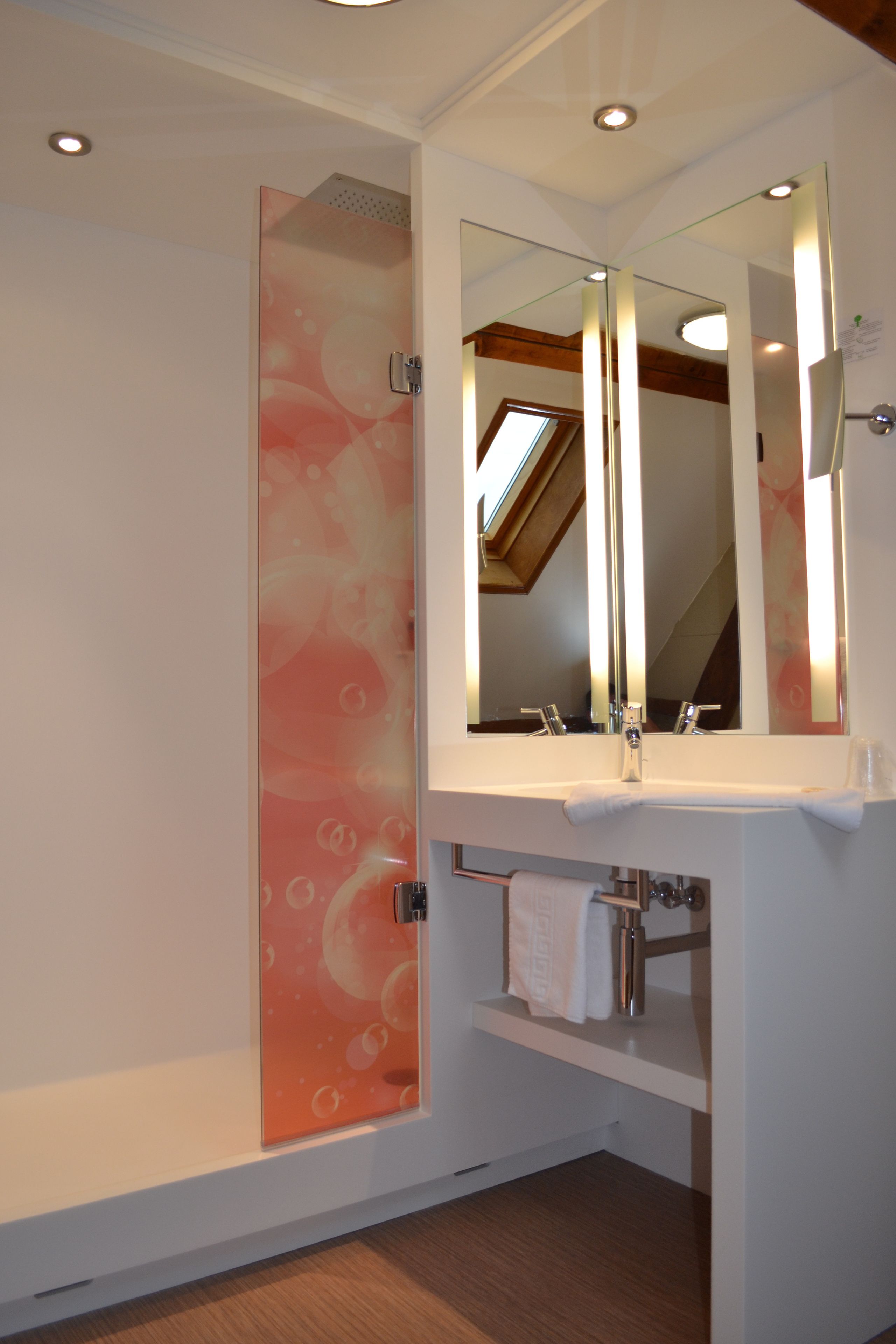 A modern bathroom with a glass shower enclosure, a large mirror, and a wooden ceiling.