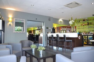 Uma área de bar moderna com assentos, balcão e uma seleção de garrafas de bebidas.
