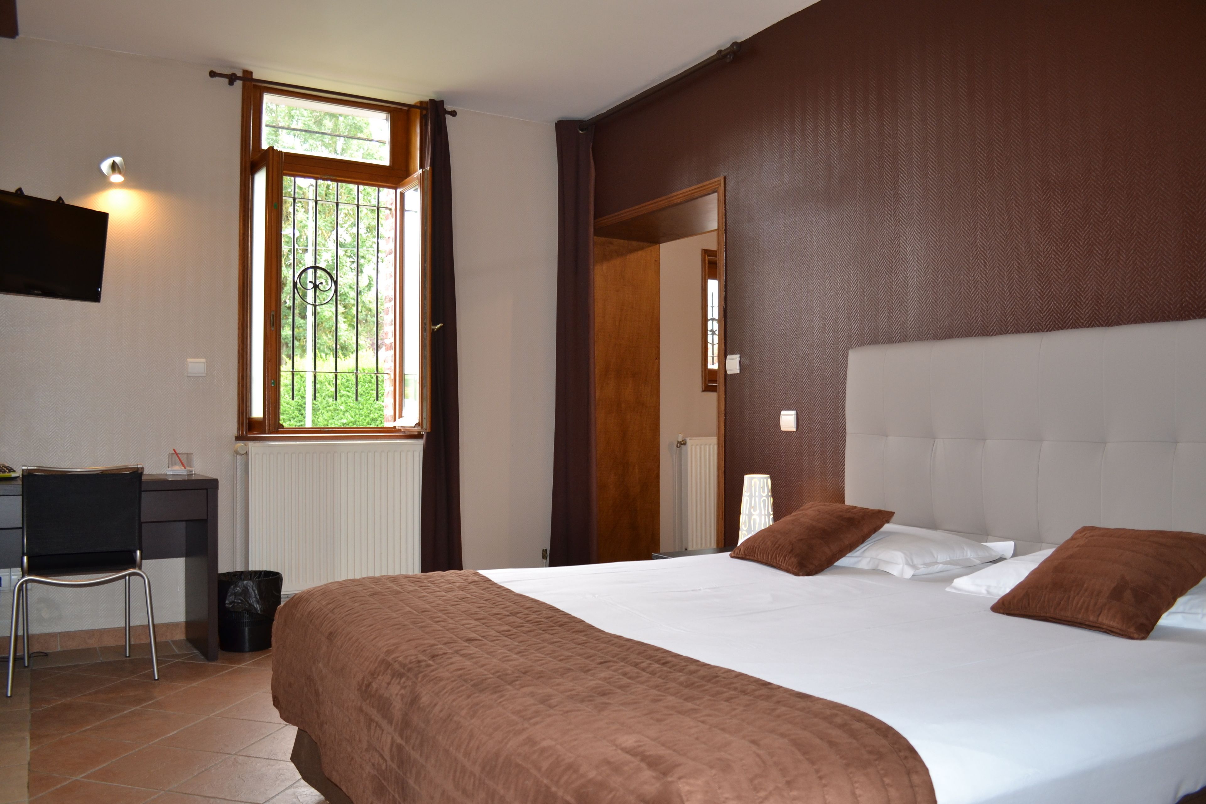 A bedroom with a large bed, a desk, and a chair.