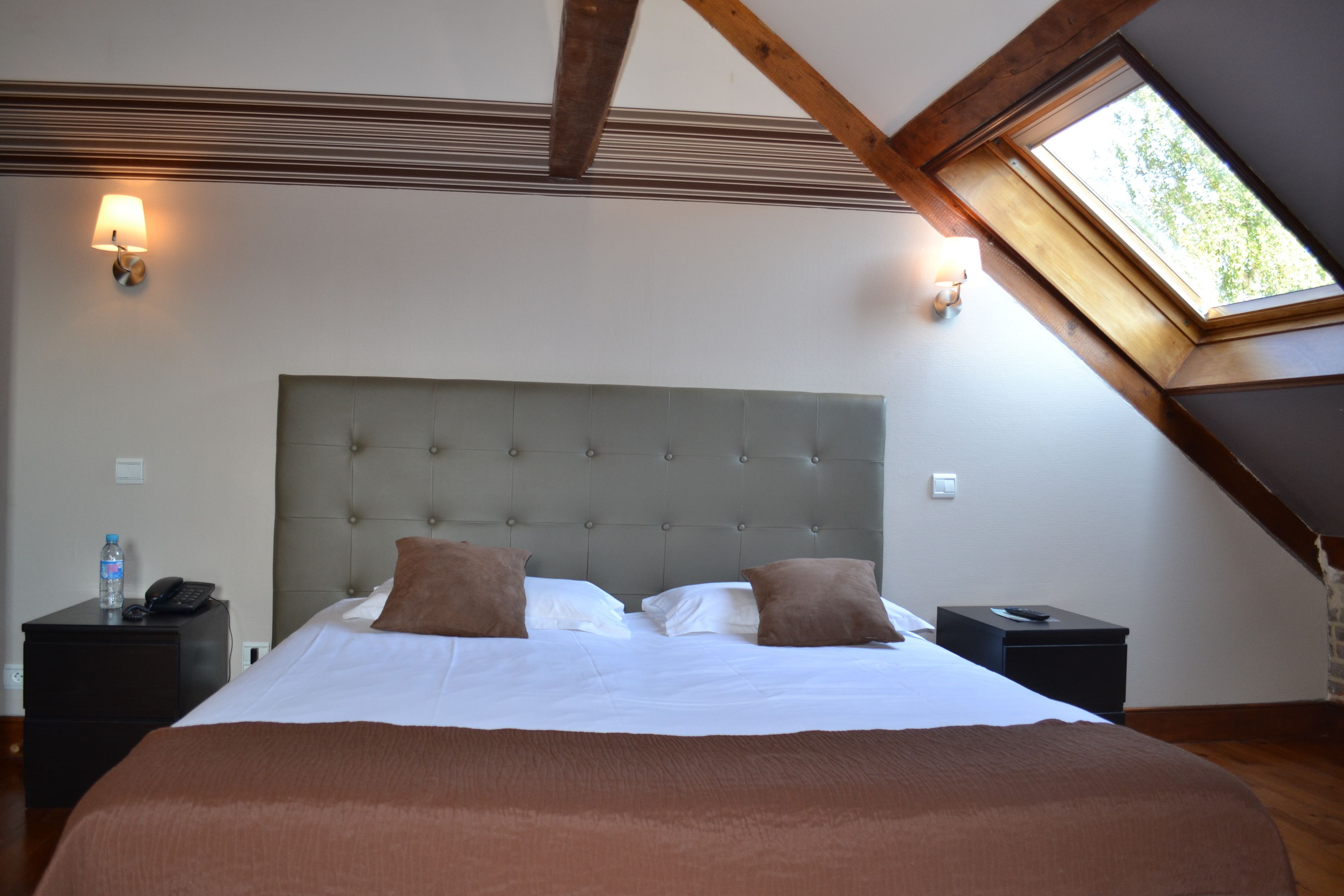 A bedroom with a large bed, two bedside tables, and a skylight.