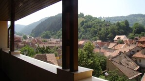 A balcony with a view of a village with traditional houses and a forested hill in the background. - Coroana Brasovului (Brasov)