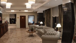 A spacious lobby with a large seating area, a reception desk, and a modern chandelier. - Coroana Brasovului (Brasov)