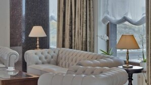 A plush, tufted sofa in a modern room with marble columns, two lamps, and a view through sheer curtains. - Coroana Brasovului (Brasov)