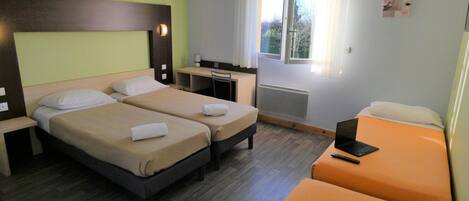 A hotel room with two beds, a desk, and a window.
