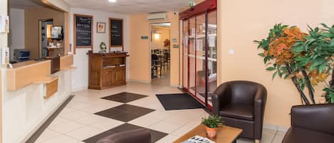 A reception area with a counter, seating, a potted plant, and a bulletin board.