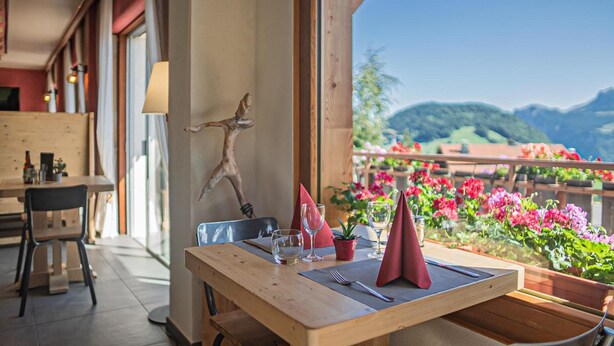Une table à manger dressée avec des verres à vin, une serviette rouge et une petite plante.
