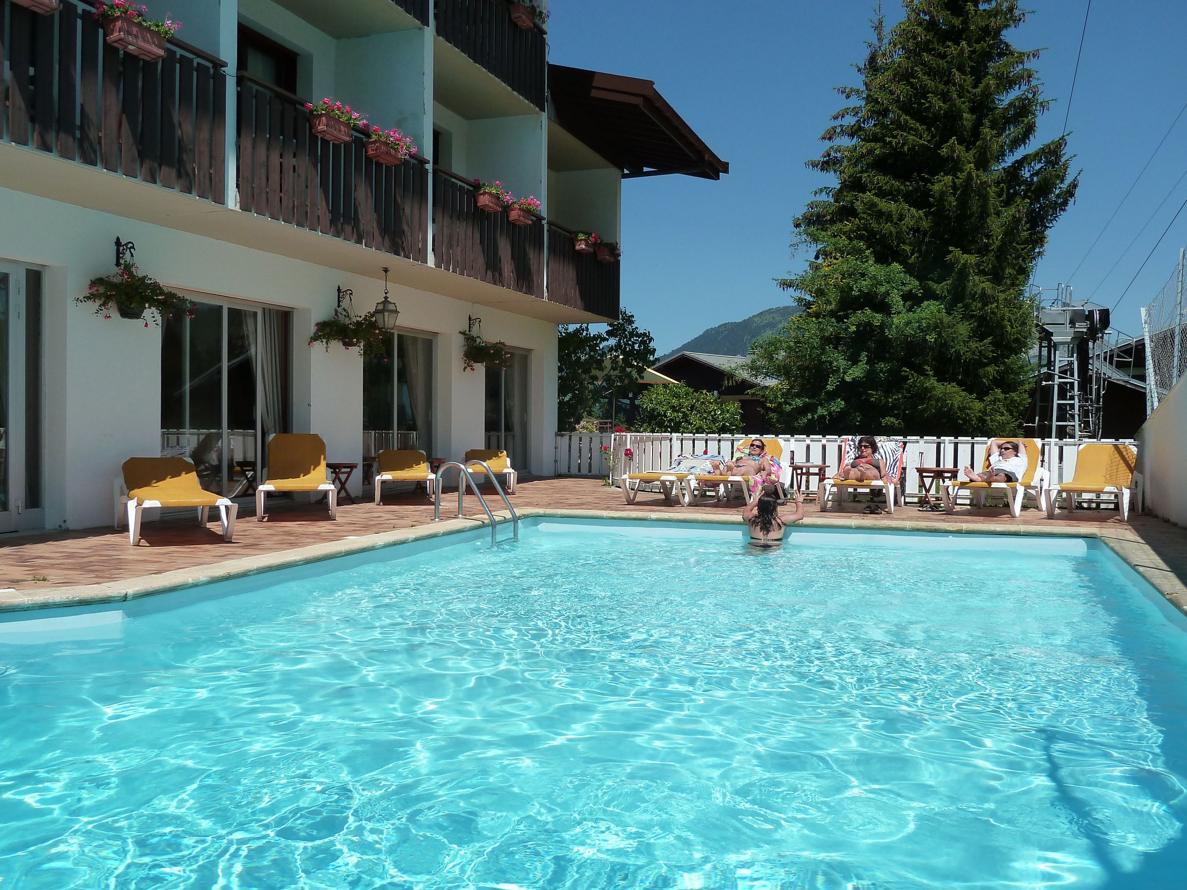 Una piscina con tumbonas y un edificio con balcones.