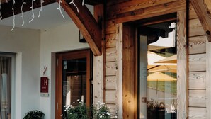 Il s’agit d’un bâtiment en bois doté d’un porche, de grandes fenêtres et d’une porte sur laquelle est apposée une enseigne. Des plantes et des fleurs en pot sont disposées sur le porche.
