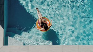 Une personne flotte sur un bouée gonflable dans une piscine dont l’eau est d’un bleu limpide.