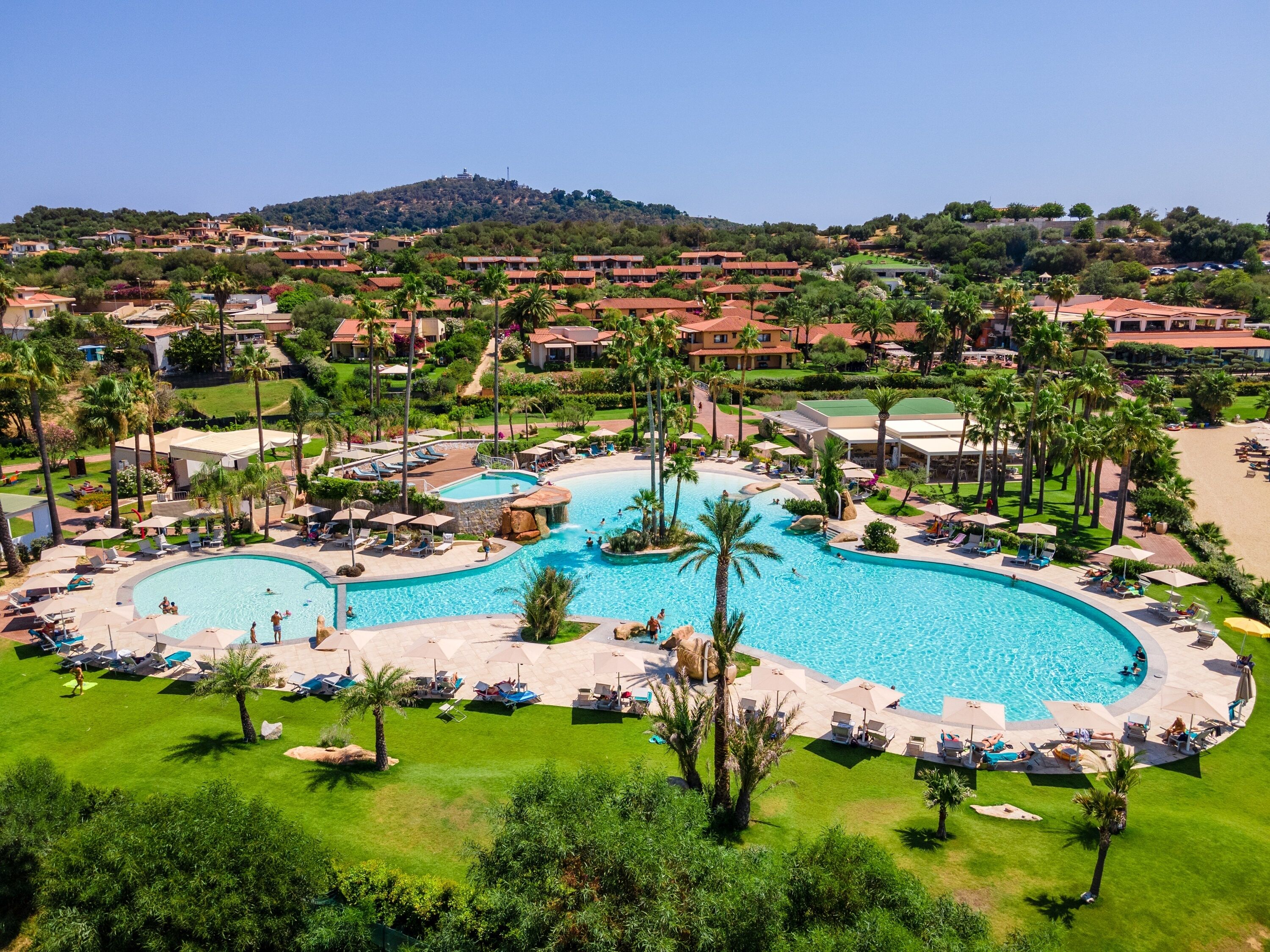 A resort with a large central pool, multiple smaller pools, and a beach area.