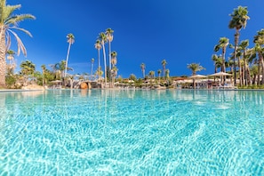 A clear blue pool surrounded by palm trees and umbrellas. - Hotel Club Saraceno (Tortoli)