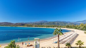 A beach with clear blue water, a row of sun loungers, and a lifeguard tower. - Hotel Club Saraceno (Tortoli)
