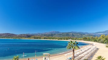 Playa privada, arena negra, sillas reclinables de playa, sombrillas