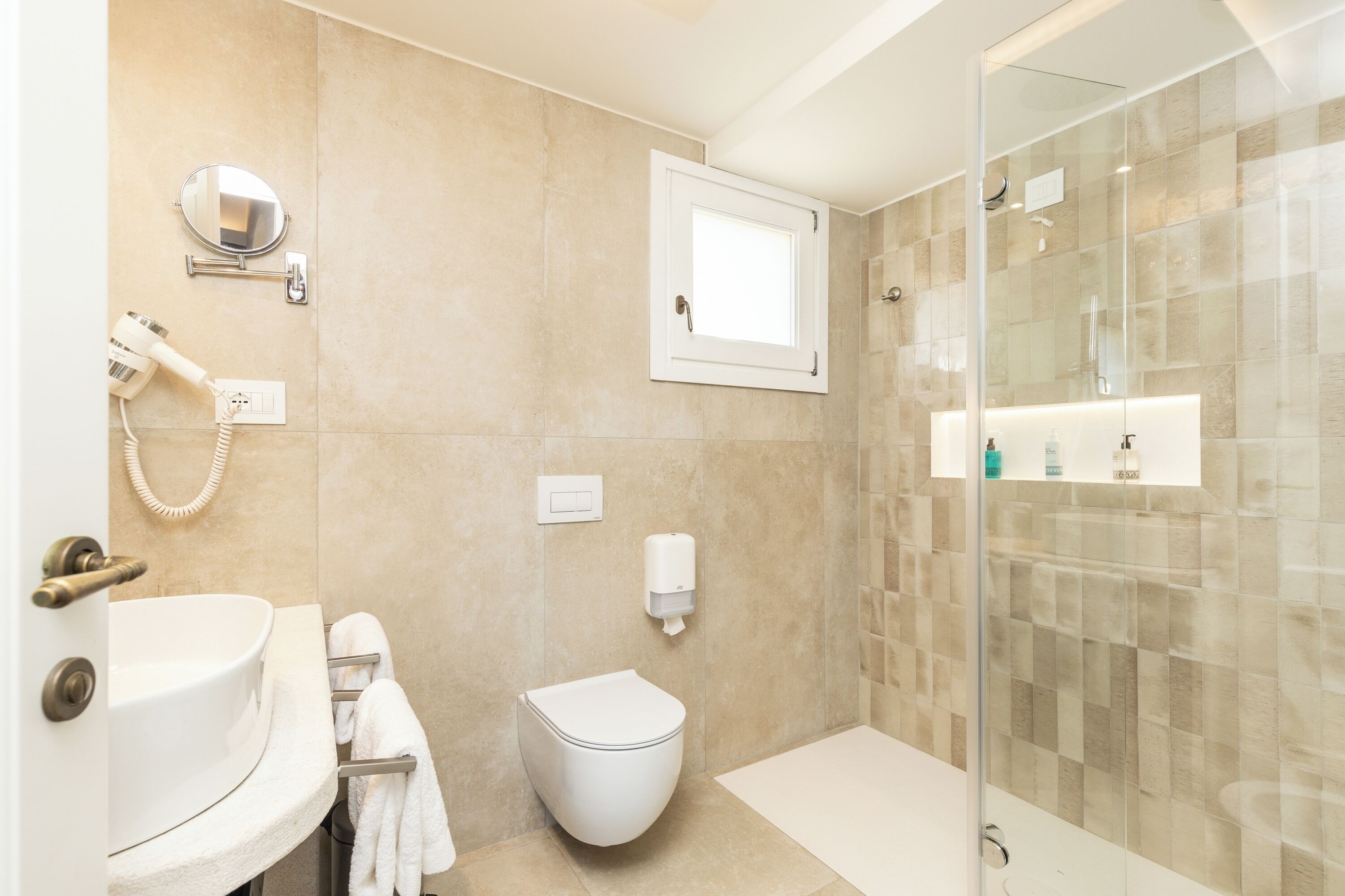 A modern bathroom with a sink, toilet, and glass shower enclosure.
