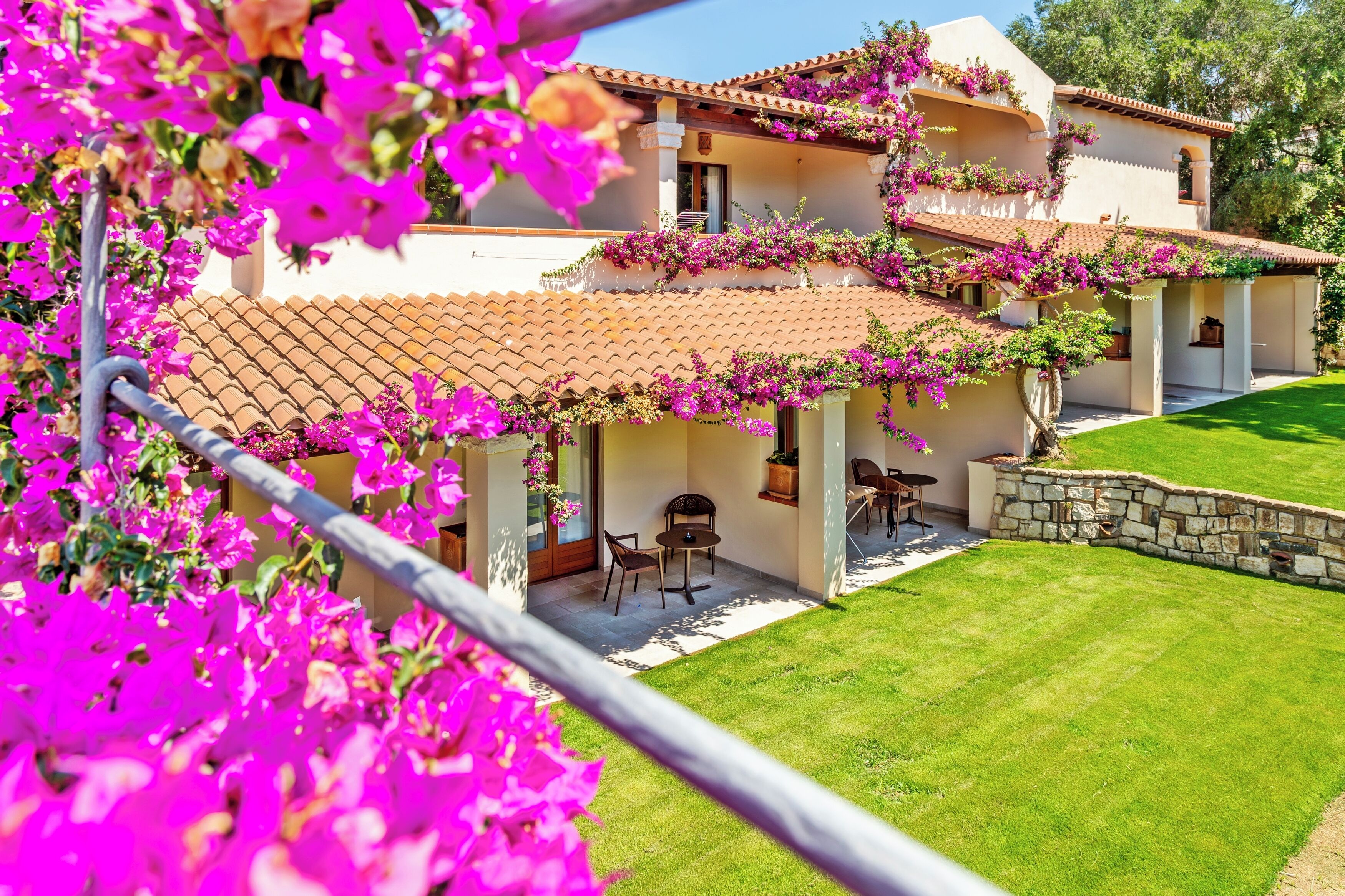 Una casa de dos plantas con techo de tejas, pared de piedra y césped bien cuidado.