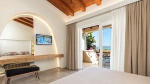 A modern hotel room with a large bed, a bench, a TV, and a balcony with a view. - Hotel Club Saraceno (Tortoli)