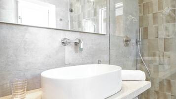 Ein Badezimmer mit einem weißen Waschbecken, einem Glasbehälter und einem Spiegel.