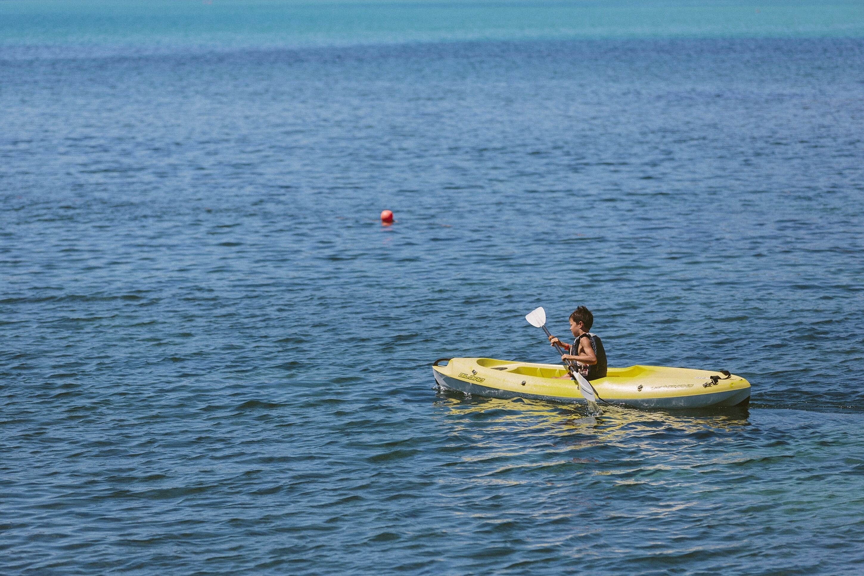 A person kayaking on a calm body of water.