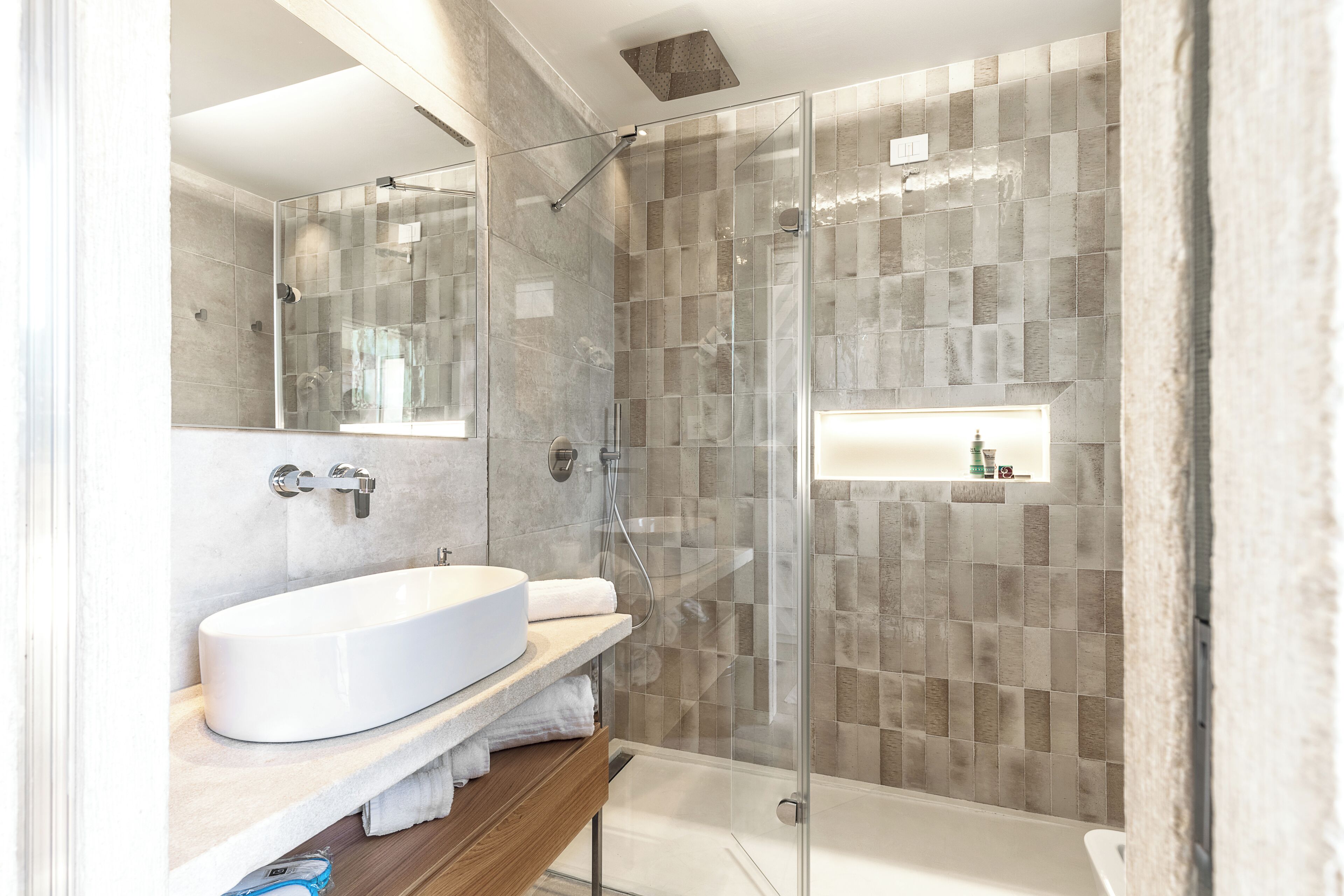 A modern bathroom with a glass-enclosed shower, a white sink, and a mirror.