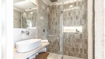 A modern bathroom with a glass-enclosed shower, a white sink, and a mirror.