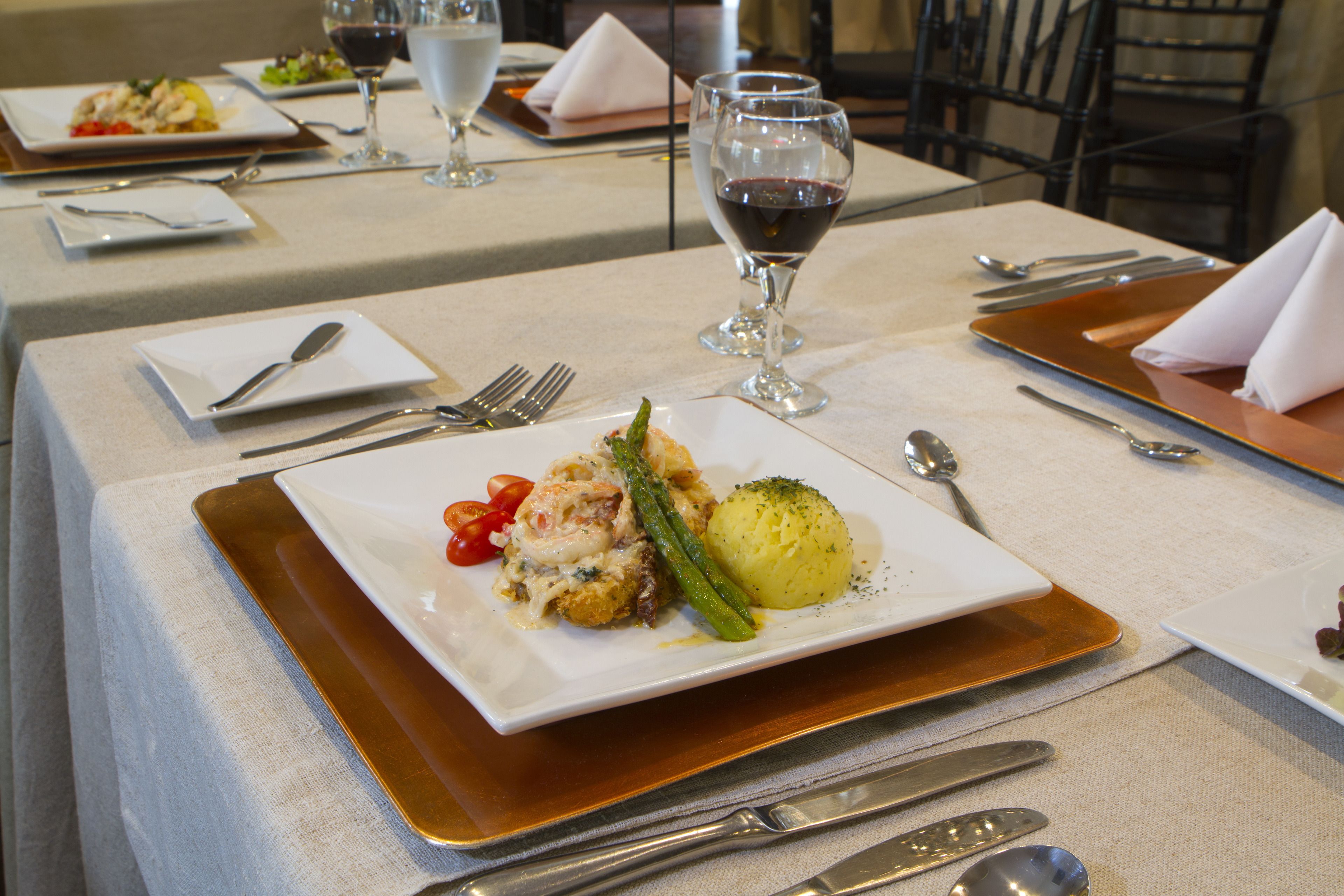 Une table à manger dressée avec des assiettes remplies de nourriture, des couverts et des verres à vin.