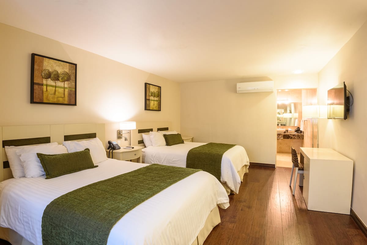Une chambre d’hôtel avec deux lits, un bureau, une chaise et une petite kitchenette.