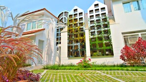 Un bâtiment moderne doté de nombreux balcons et d’un jardin bien entretenu.