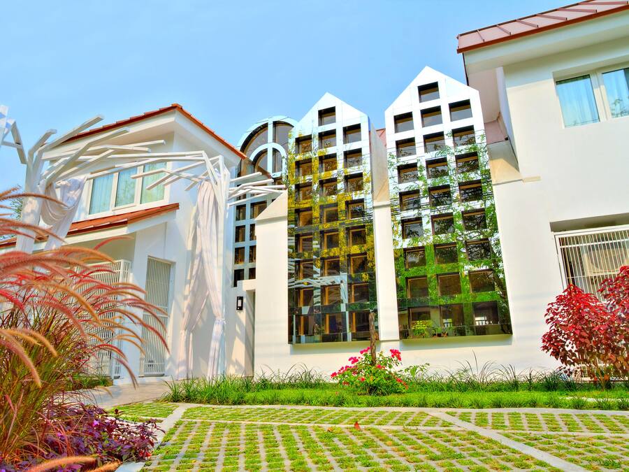 A modern building with multiple balconies and a well-maintained garden.