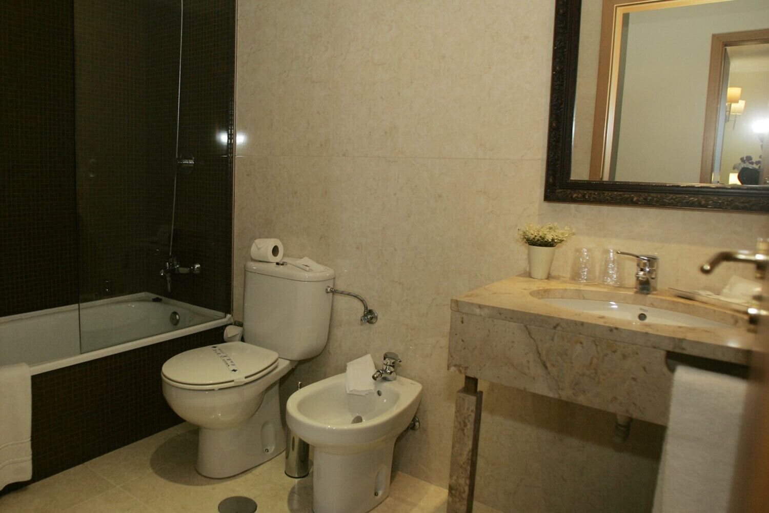 A bathroom with a bathtub, toilet, bidet, and sink.