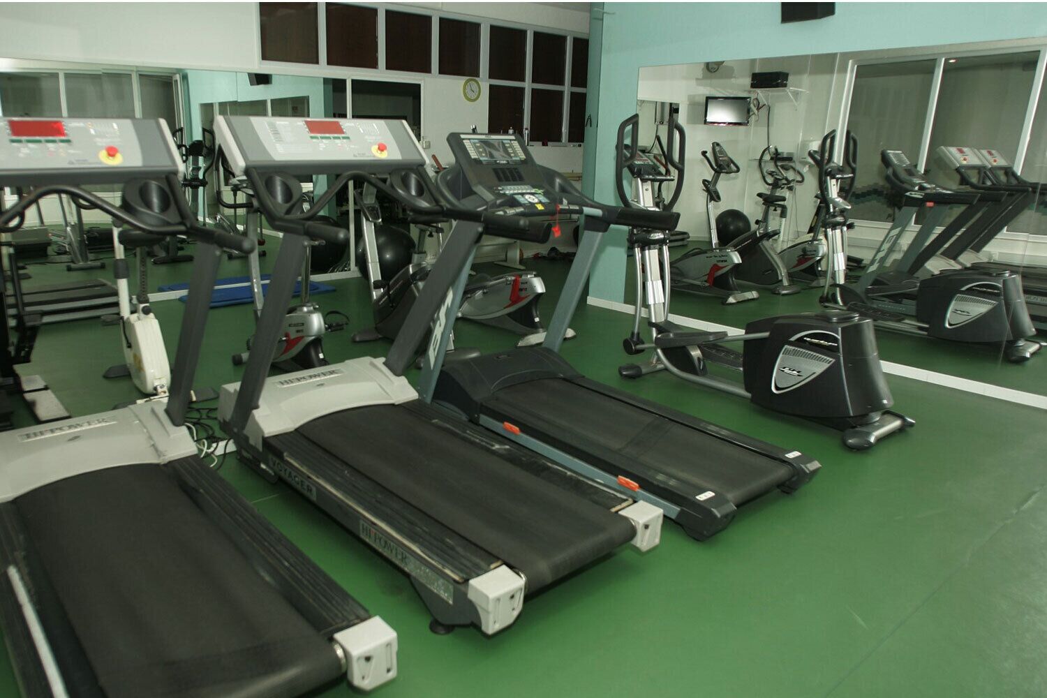 Un gimnasio con múltiples cintas de correr, elípticas y bicicletas estáticas.