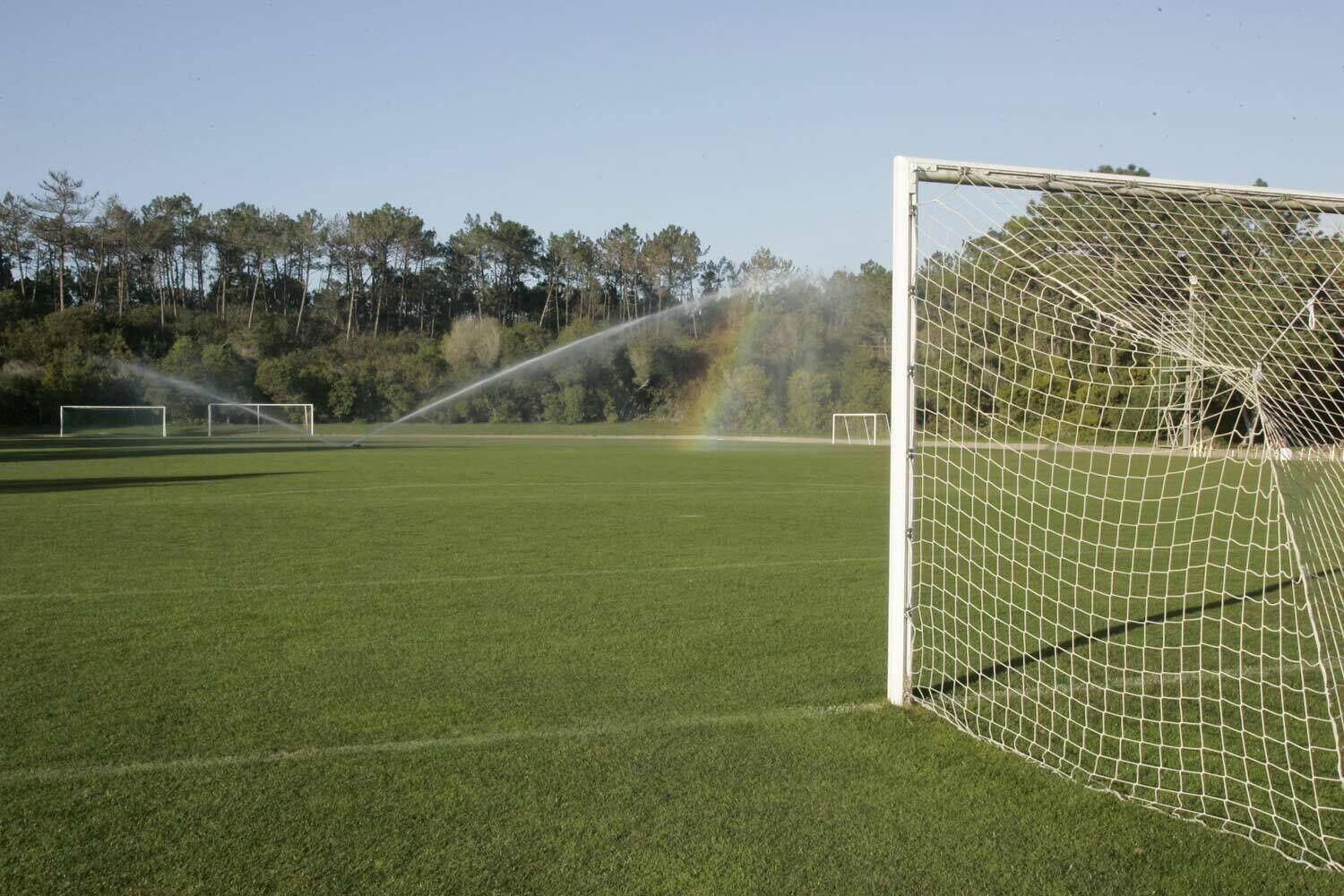 A soccer field with a goalpost and a rainbow in the background.