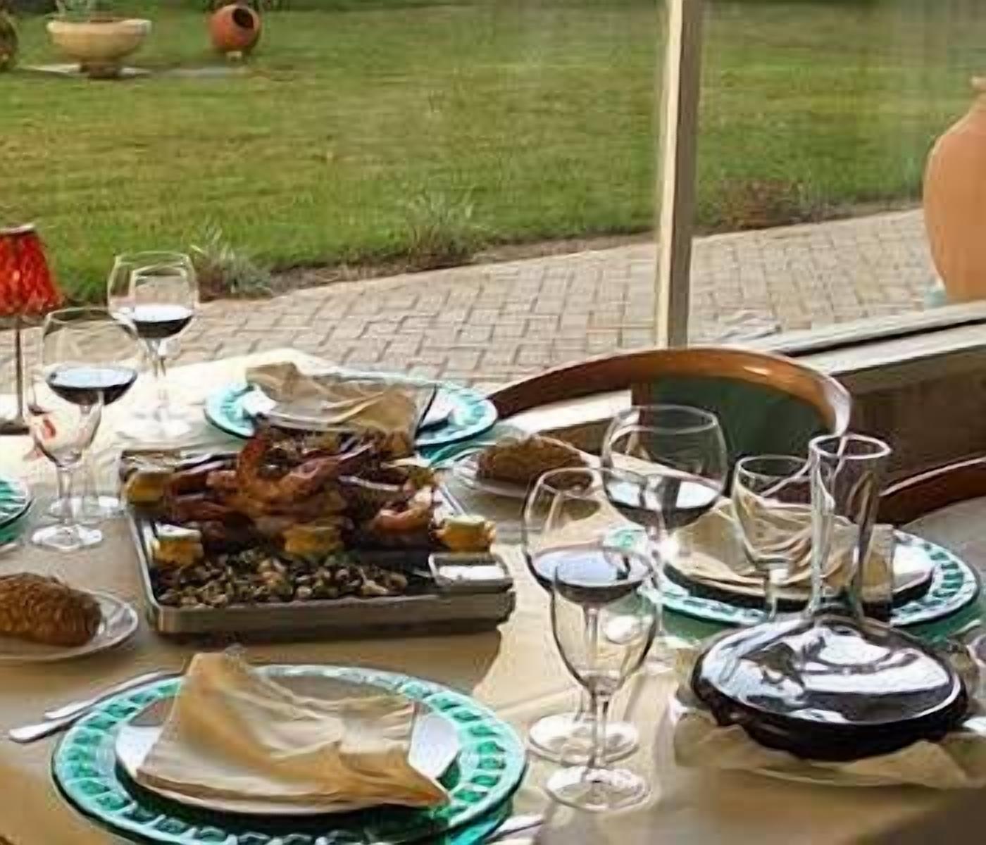 A dining table set with plates, glasses, and a variety of food items.