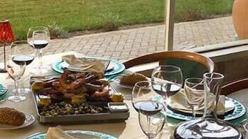 Una mesa de comedor dispuesta con platos, vasos y diversos alimentos.