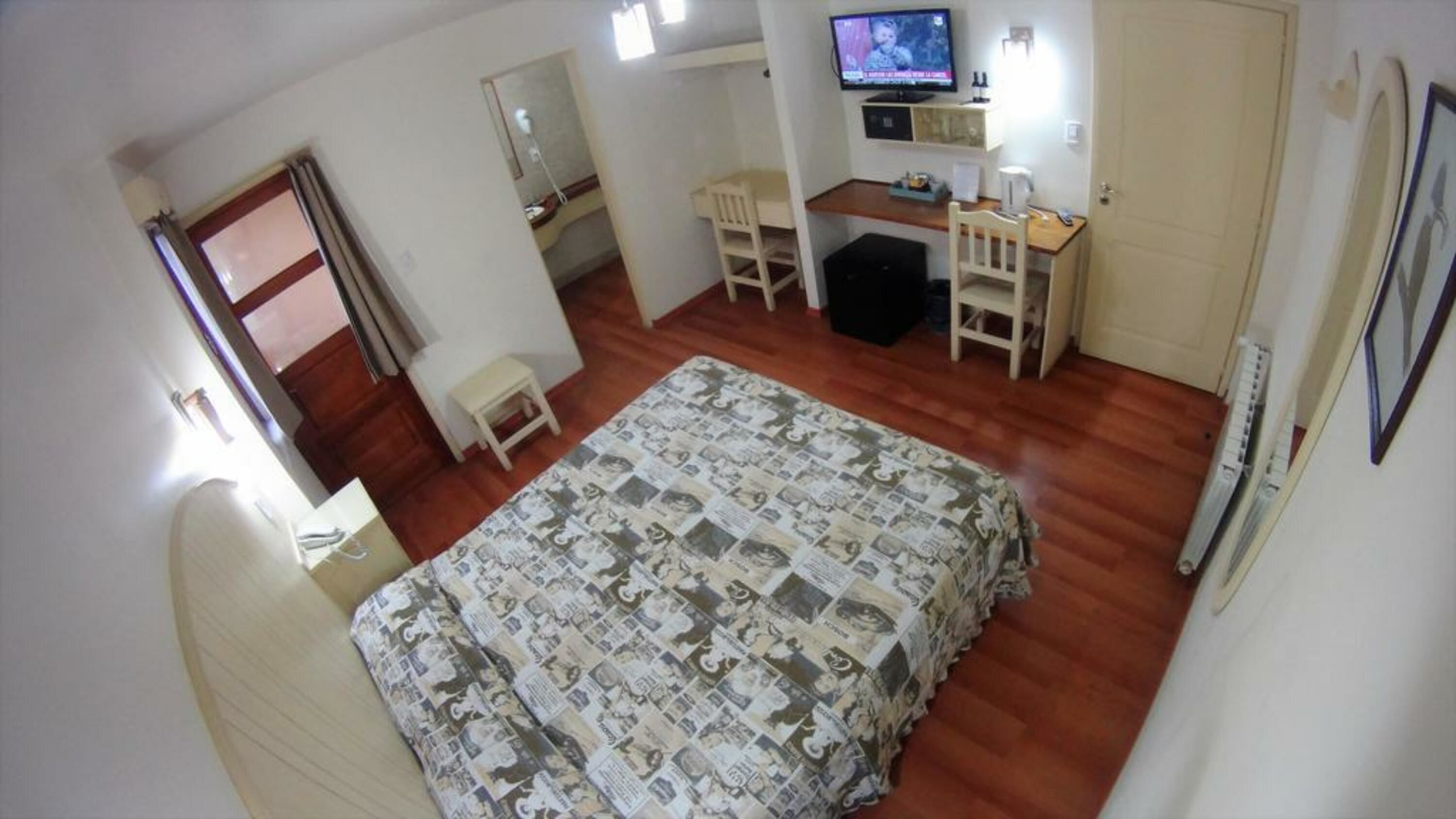Un dormitorio con cama, escritorio, silla, televisor y armario.
