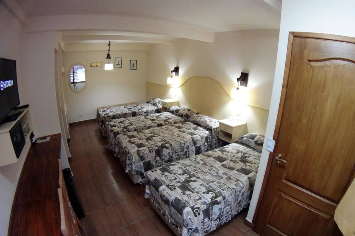 A hotel room with two beds, a wooden door, and a television on a stand.