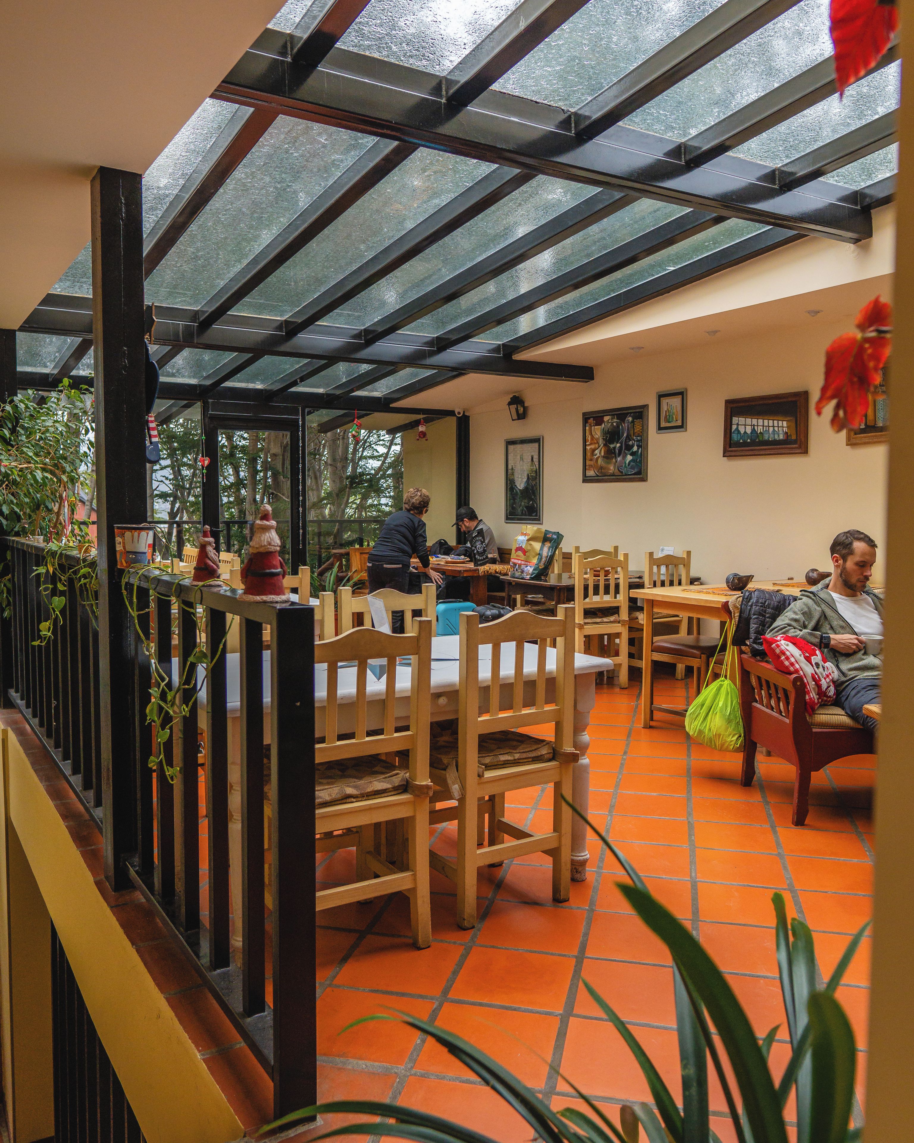 Una cafetería con sillas y mesas de madera, techo de cristal y vistas al exterior.
