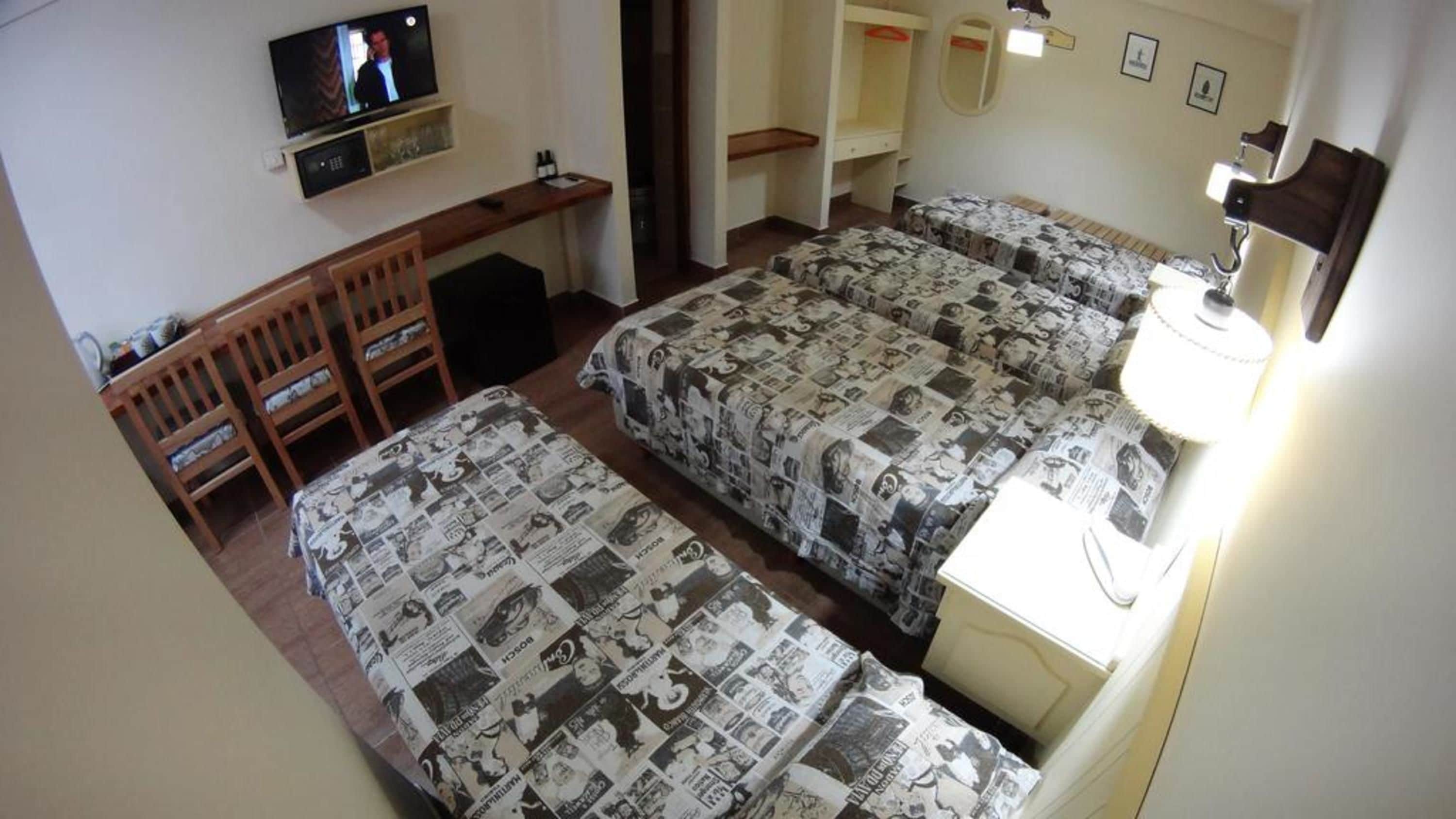 Una habitación con dos camas, un escritorio, un televisor y una lámpara.