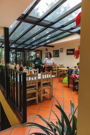 An indoor space with a glass ceiling, wooden furniture, and tiled flooring. - Rosa de Los Vientos (Ushuaia)