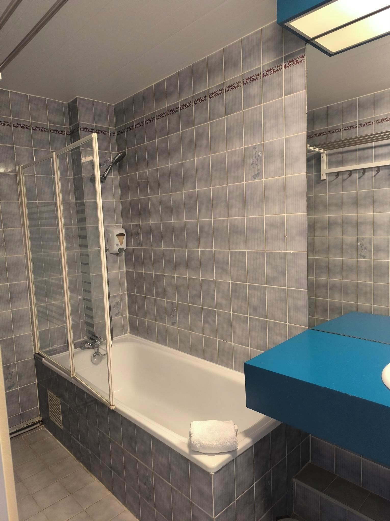 Un bagno con doccia, vasca e un mobile lavabo blu.