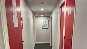 A hallway with red doors, a framed picture on the wall, and a carpeted floor.