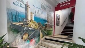 A reception area with a mural depicting a coastal scene, a staircase, and reception signage.