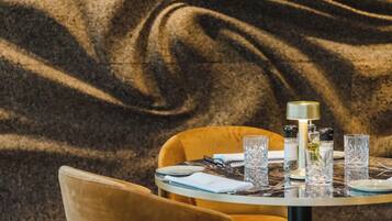 A dining table set with plates, glasses, and cutlery, with a textured wall in the background.