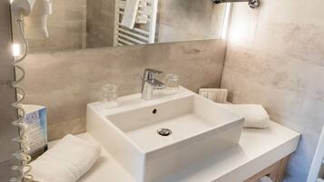 Une salle de bain moderne avec un grand lavabo, un miroir et un porte-serviettes.