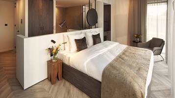 Una habitación de hotel moderna con una cama grande, una mesita de noche con un florero, una silla y un espejo grande sobre la cama.