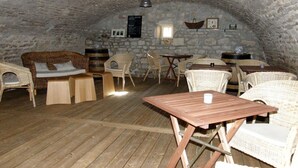 Un comedor rústico con mobiliario de mimbre, paredes de piedra y piso de madera.