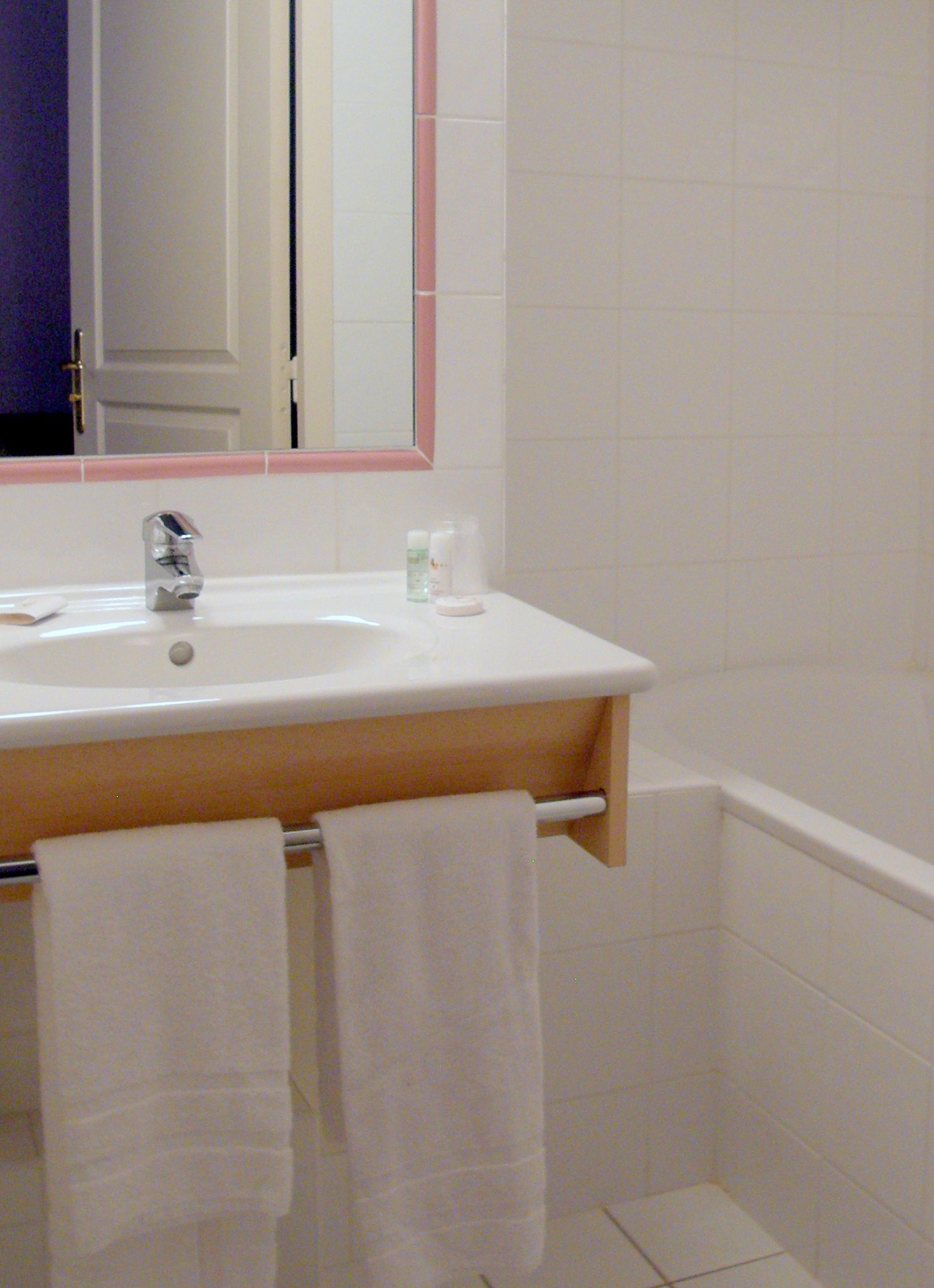 A bathroom with a white sink, a mirror, and two towels hanging on a rack.