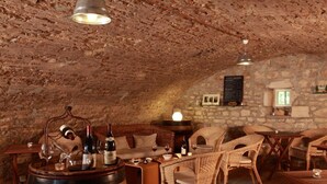 Una bodega rústica con barriles de madera, muebles de mimbre y paredes de piedra.