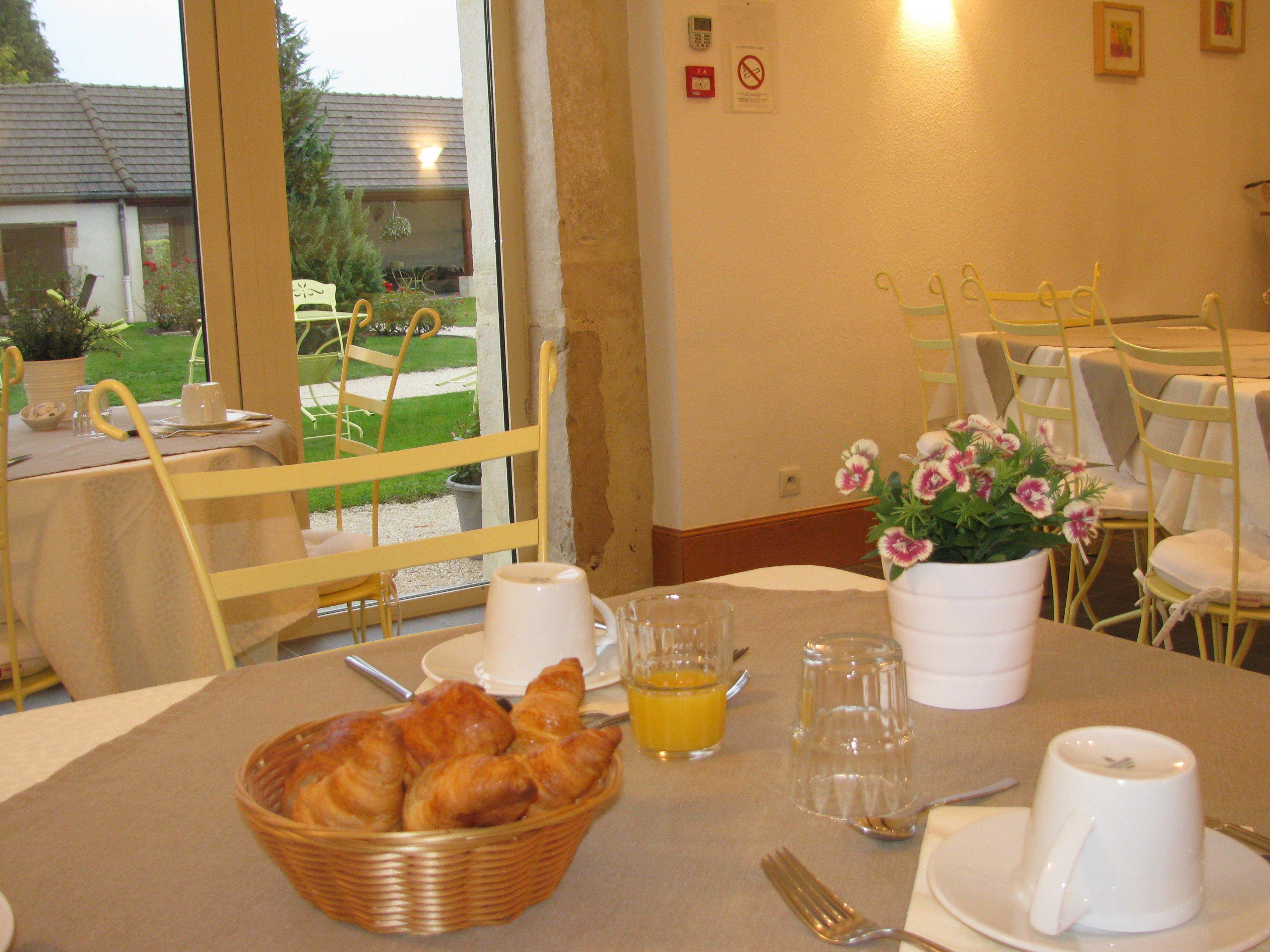 A breakfast setup with croissants, juice, and a flower vase.